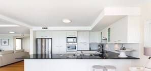 Een moderne keuken met witte kasten, roestvrijstalen apparatuur en een zwart aanrecht.