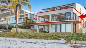 Una casa moderna de dos pisos con balcón, ventanas amplias y una flecha roja señalando la casa.