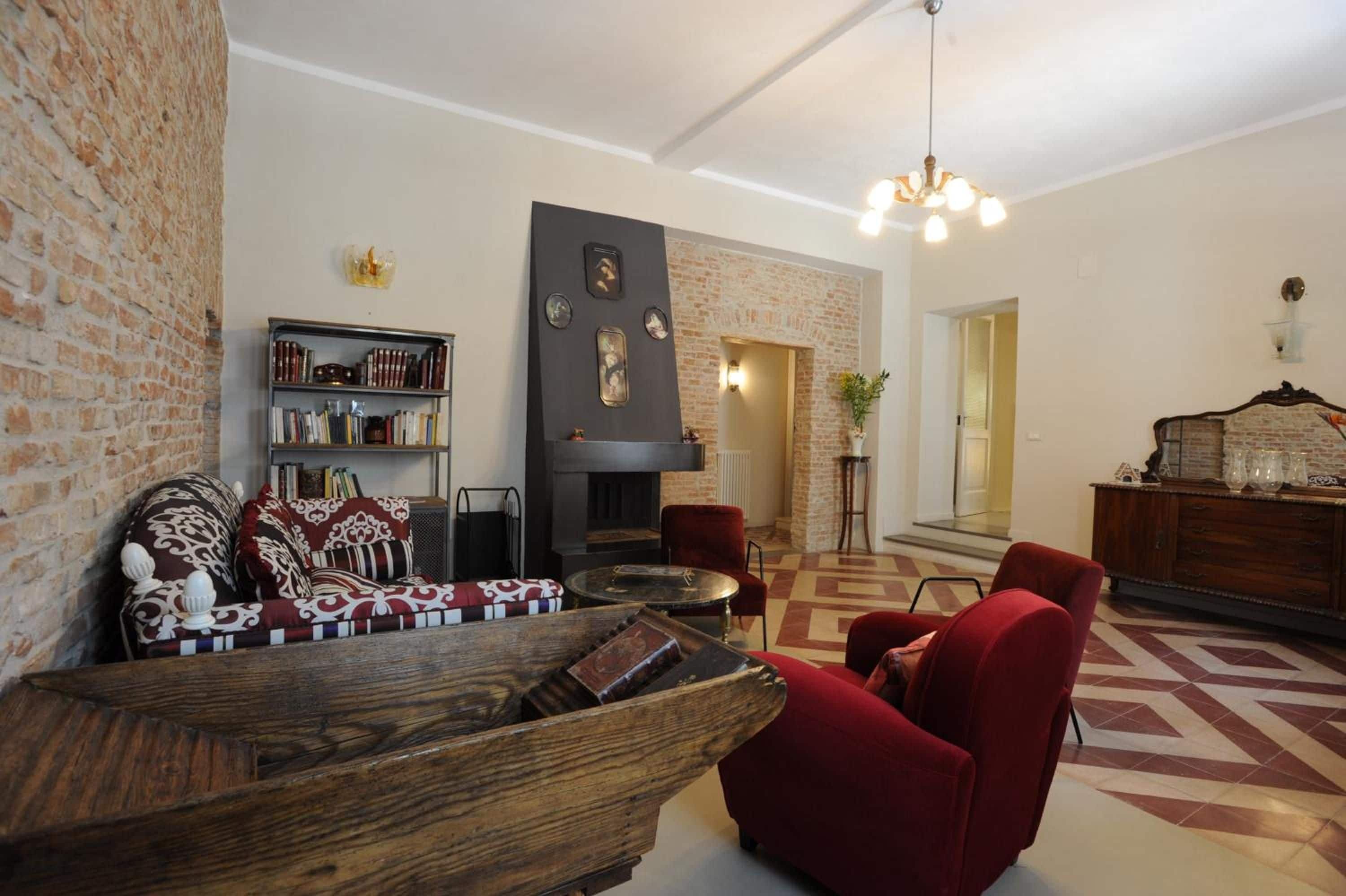 A living room with a fireplace, red armchairs, a wooden coffee table, and a bookshelf.