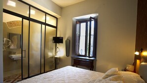 Een slaapkamer met een groot bed, een raam met uitzicht, een spiegel en een nachtkastje.