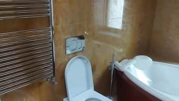 A bathroom with a bidet, toilet, and bathtub.