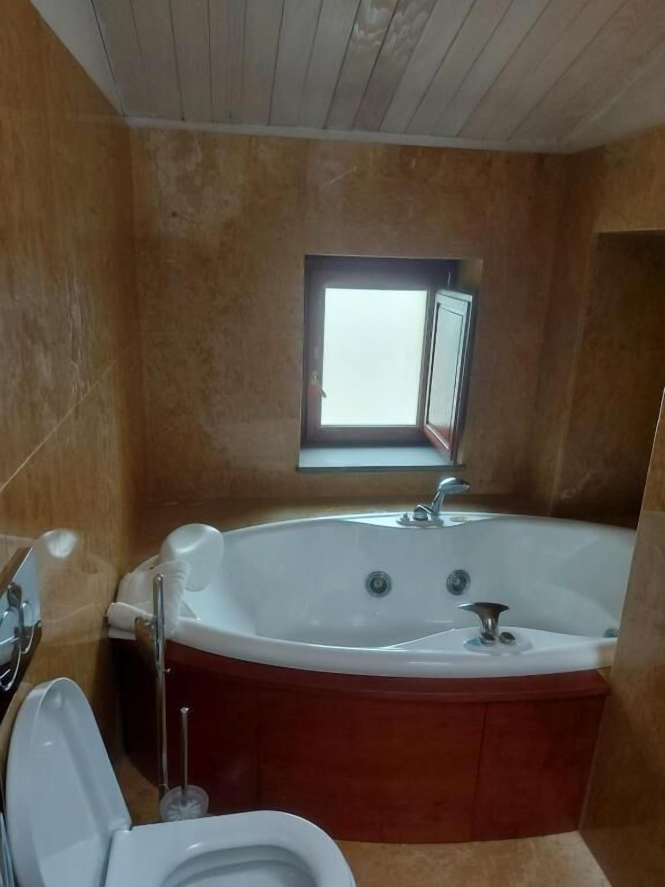 Un baño con bañera, inodoro y ventana.