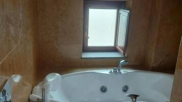 Un baño con bañera, inodoro y ventana.