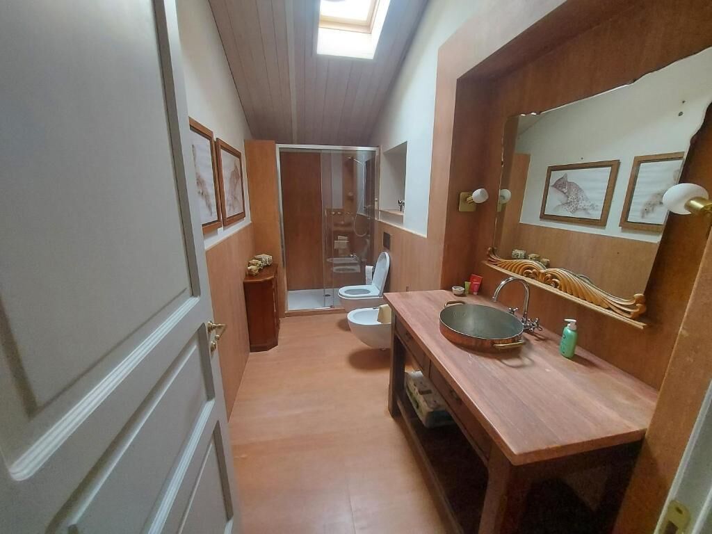 A bathroom with a wooden vanity, a large mirror, and a shower area.