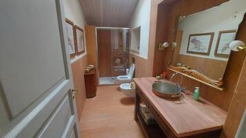 A bathroom with a wooden vanity, a large mirror, and a shower area.