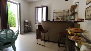 Een keuken met een bar, een groene stoel en een taart op een presentatietafel.