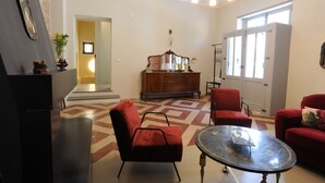 Een woonkamer met een rode bank, een ronde salontafel en een houten kast.