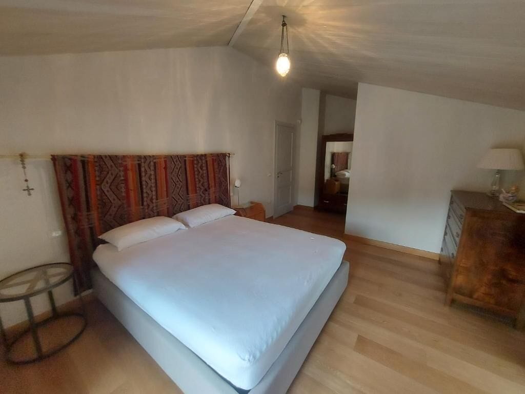 A bedroom with a bed, a round table, and a dresser.