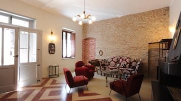 A living room with a brick wall, a sofa, red chairs, and a fireplace.