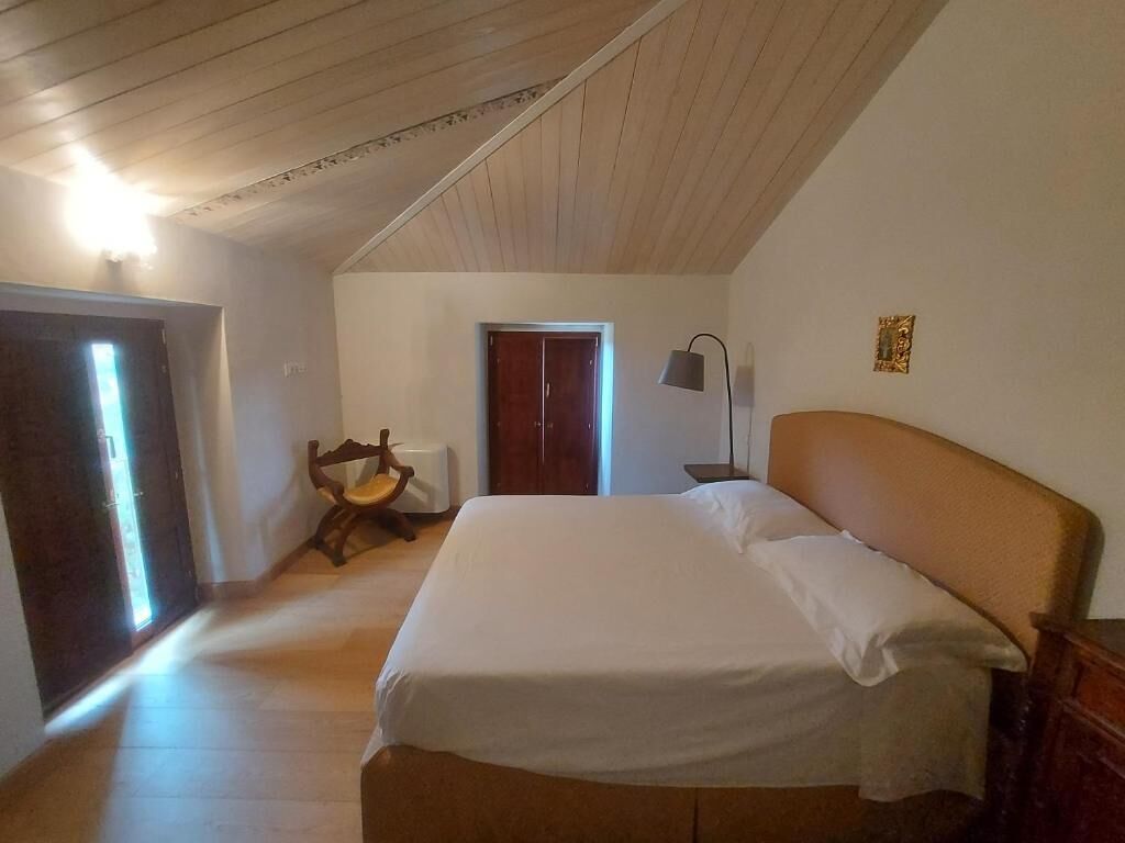 A room with a bed, a chair, a desk, and a lamp.