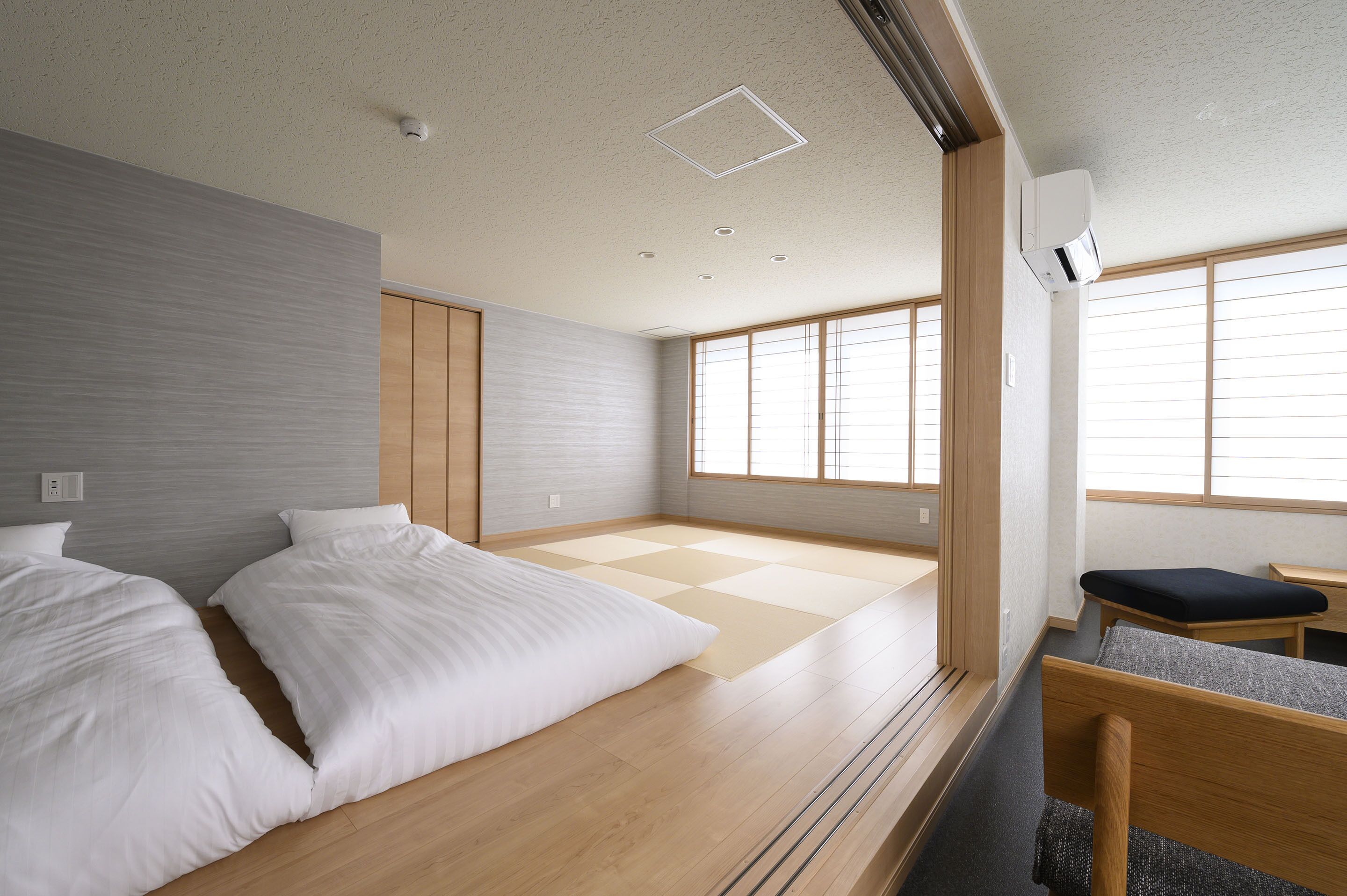 Ein modernes Hotelzimmer mit Tatami-Boden, Holzmöbeln und großen Fenstern.