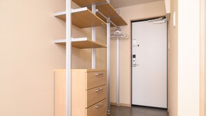 Un pasillo con un aparador de madera, una estantería metálica y una puerta.