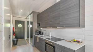 A modern kitchen with grey cabinetry, a built-in oven, a microwave, and a sink.