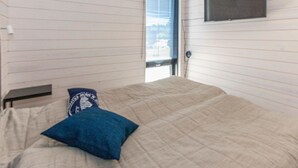A room with a bed, a window, and a mounted TV.