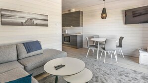 A modern living room with a grey sofa, a round coffee table, and a dining area with a white table and grey chairs.