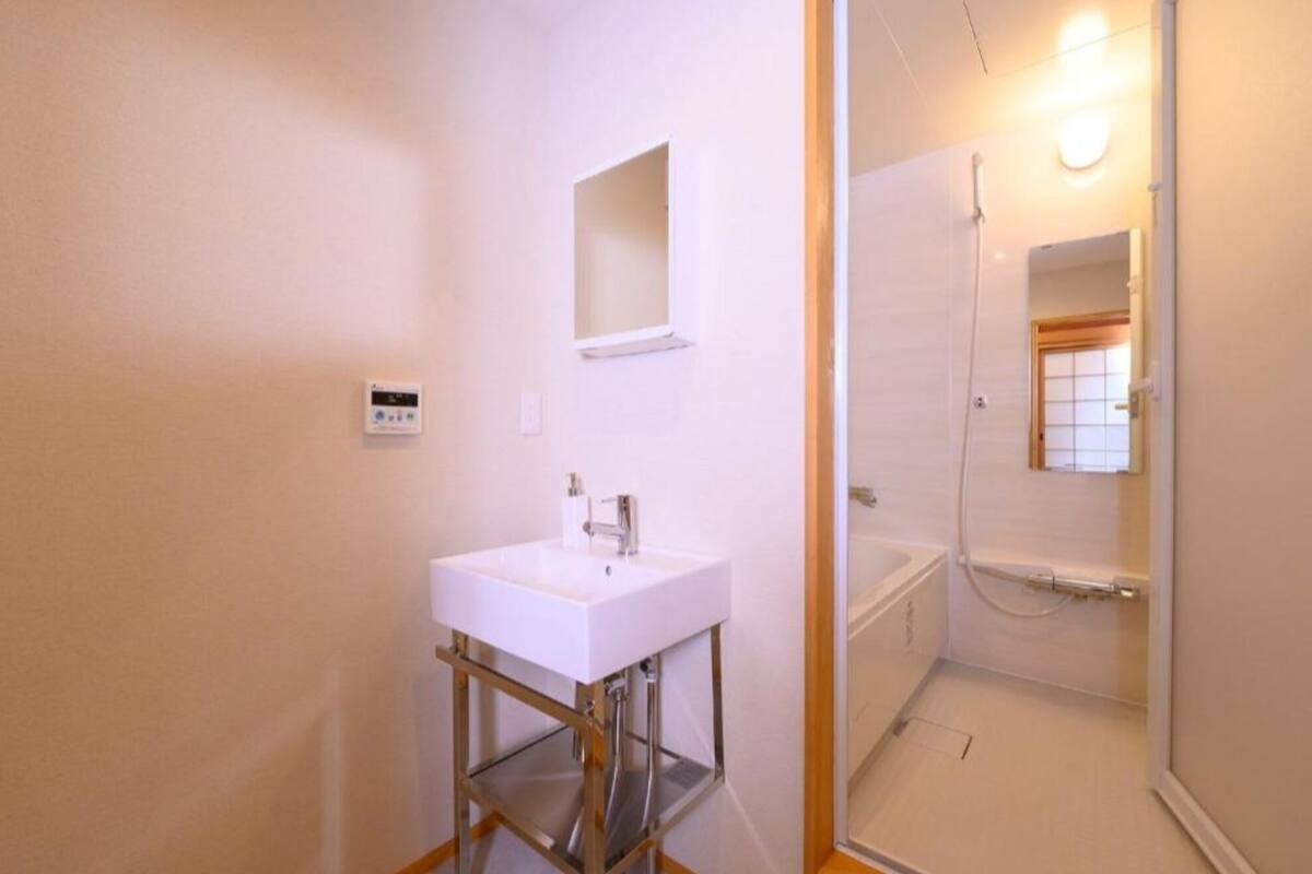 A bathroom with a white sink, a mirror, and a shower area.