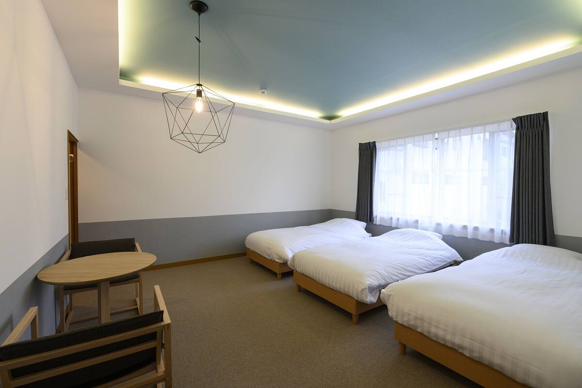 A hotel room with two beds, a desk, and a chair.
