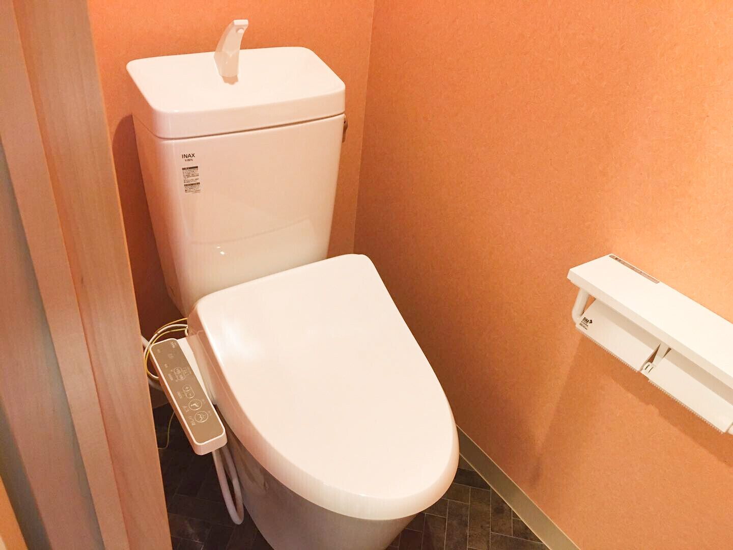 A white toilet with a control panel, a white flush tank, and a white flush handle.