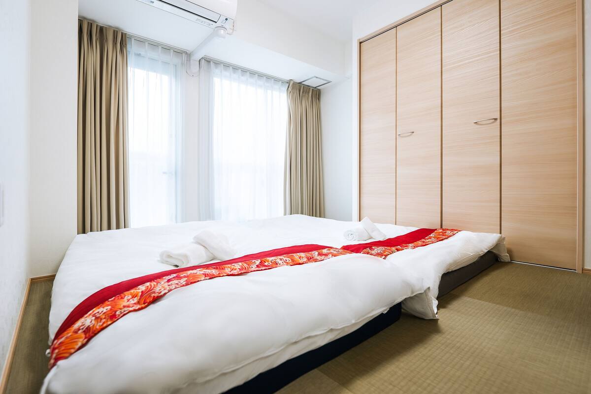 A hotel room with a bed, a wardrobe, and a window with curtains.