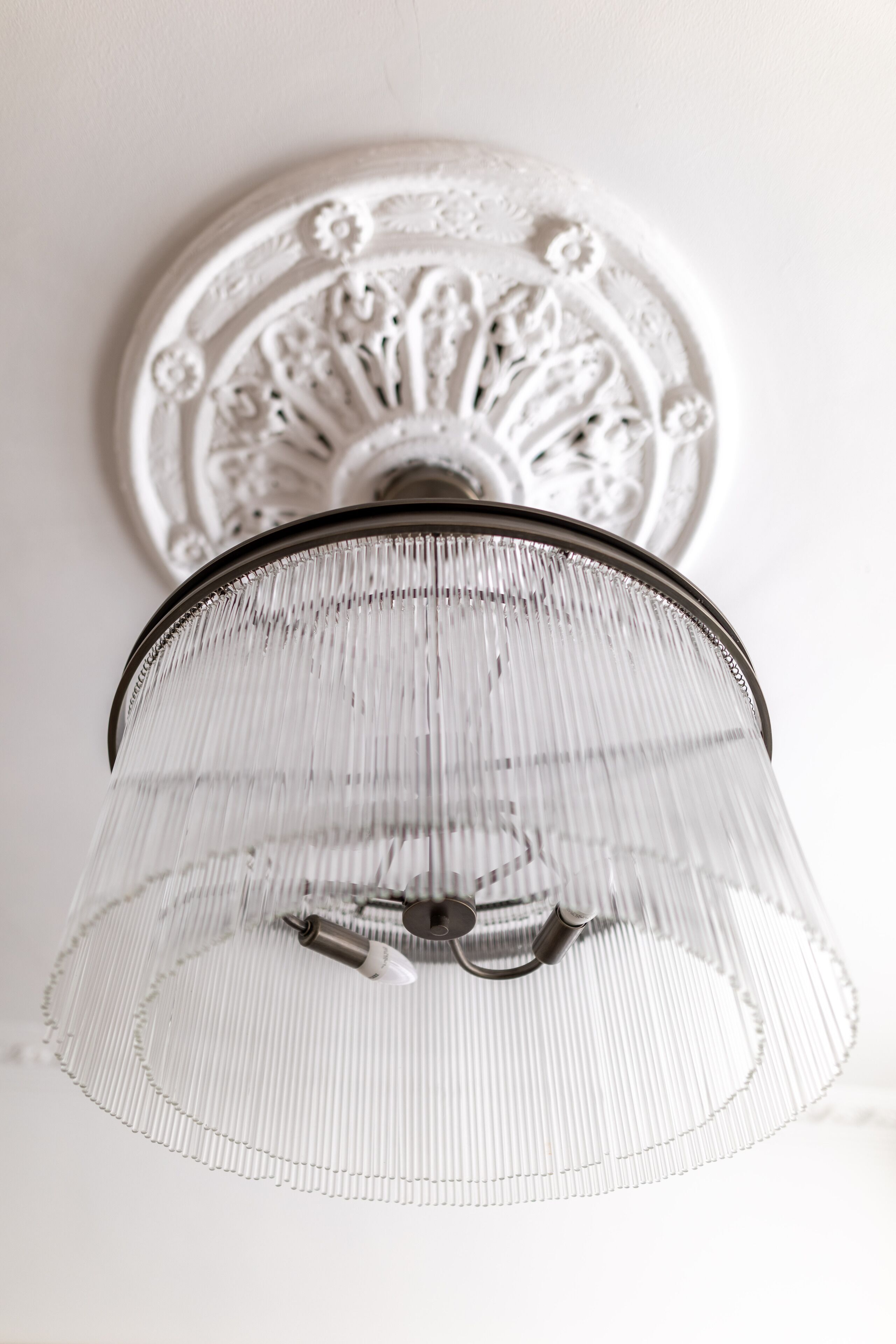 A ceiling light fixture with a clear glass shade and a decorative metal plate.