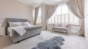 A bedroom with a large bed, a bench, and a fluffy rug. - Stroll To The City Centre In From Chic Refurbished Townhouse (Cardiff)