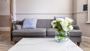 A living room with a grey sofa, a marble coffee table, and a vase of white flowers. - Stroll To The City Centre In From Chic Refurbished Townhouse (Cardiff)