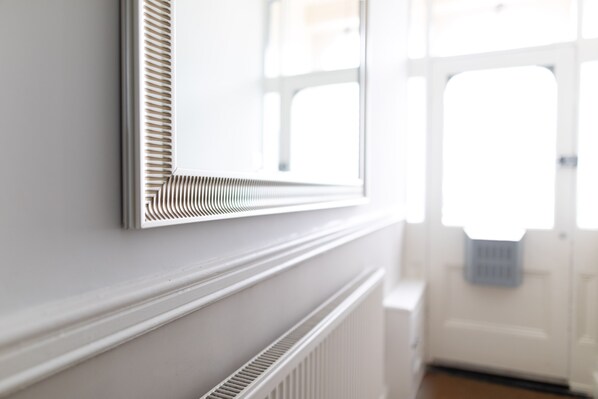 Un radiador blanco con una rejilla de ventilación, una ventana y una puerta en una habitación.