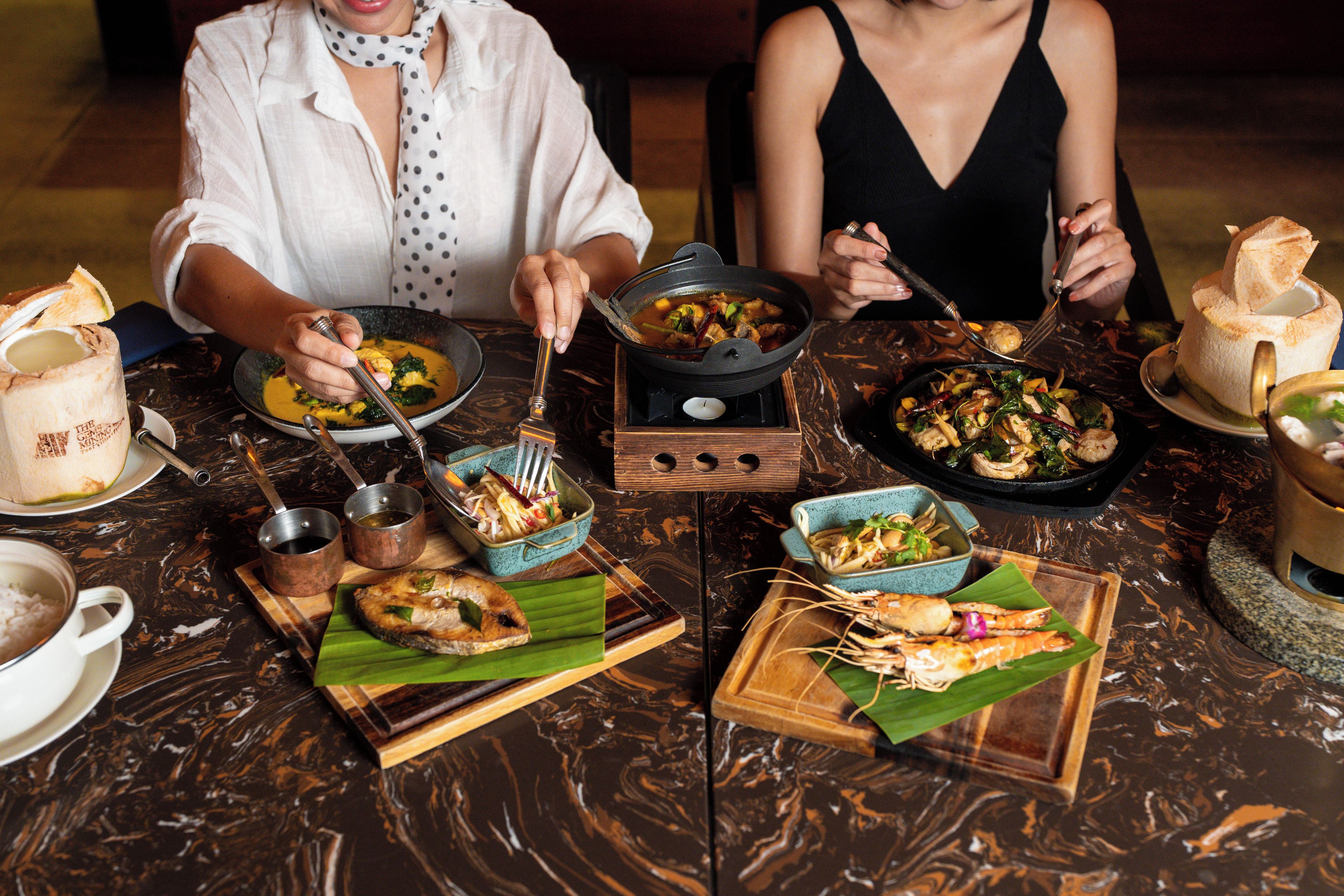Una mesa de comedor con diferentes platos, cubiertos y una vela.
