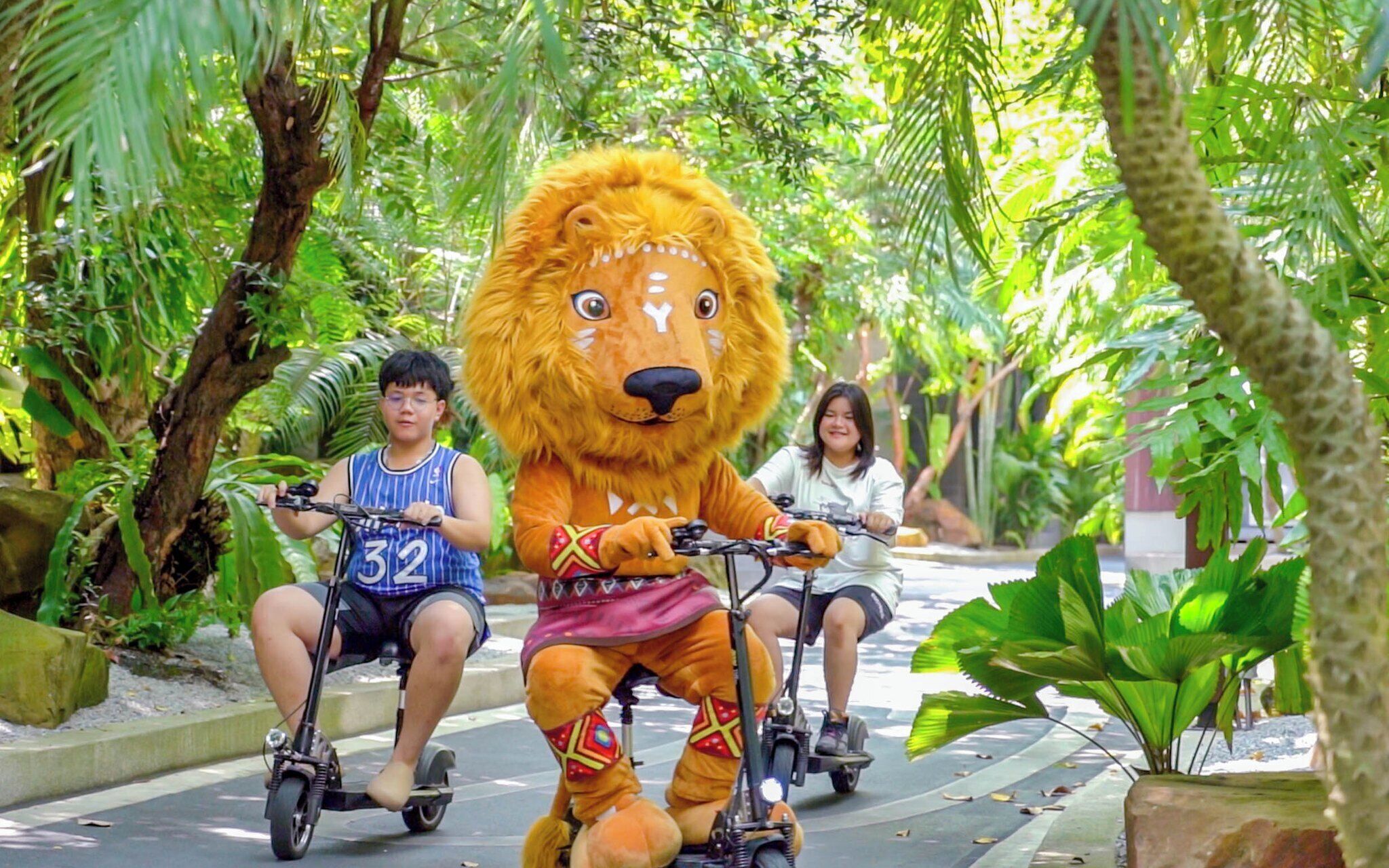 A person in a lion costume riding a scooter in a lush, green environment.