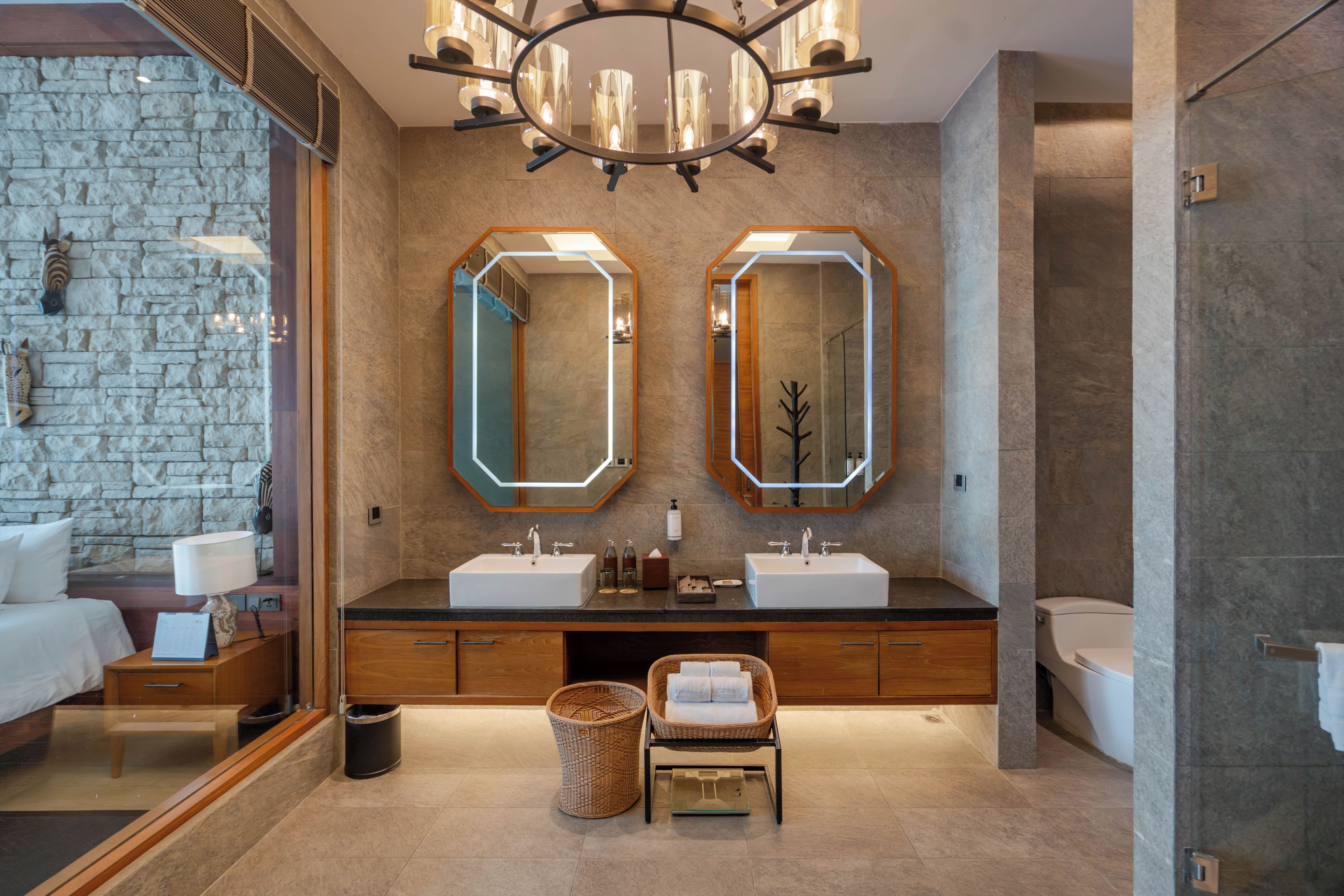 A modern bathroom with two sinks, a large mirror, and a chandelier.
