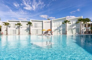 Un hotel con piscina, palmeras y cielo despejado.