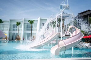 Un toboggan aquatique au bord d’une piscine, avec un bâtiment moderne en arrière-plan.