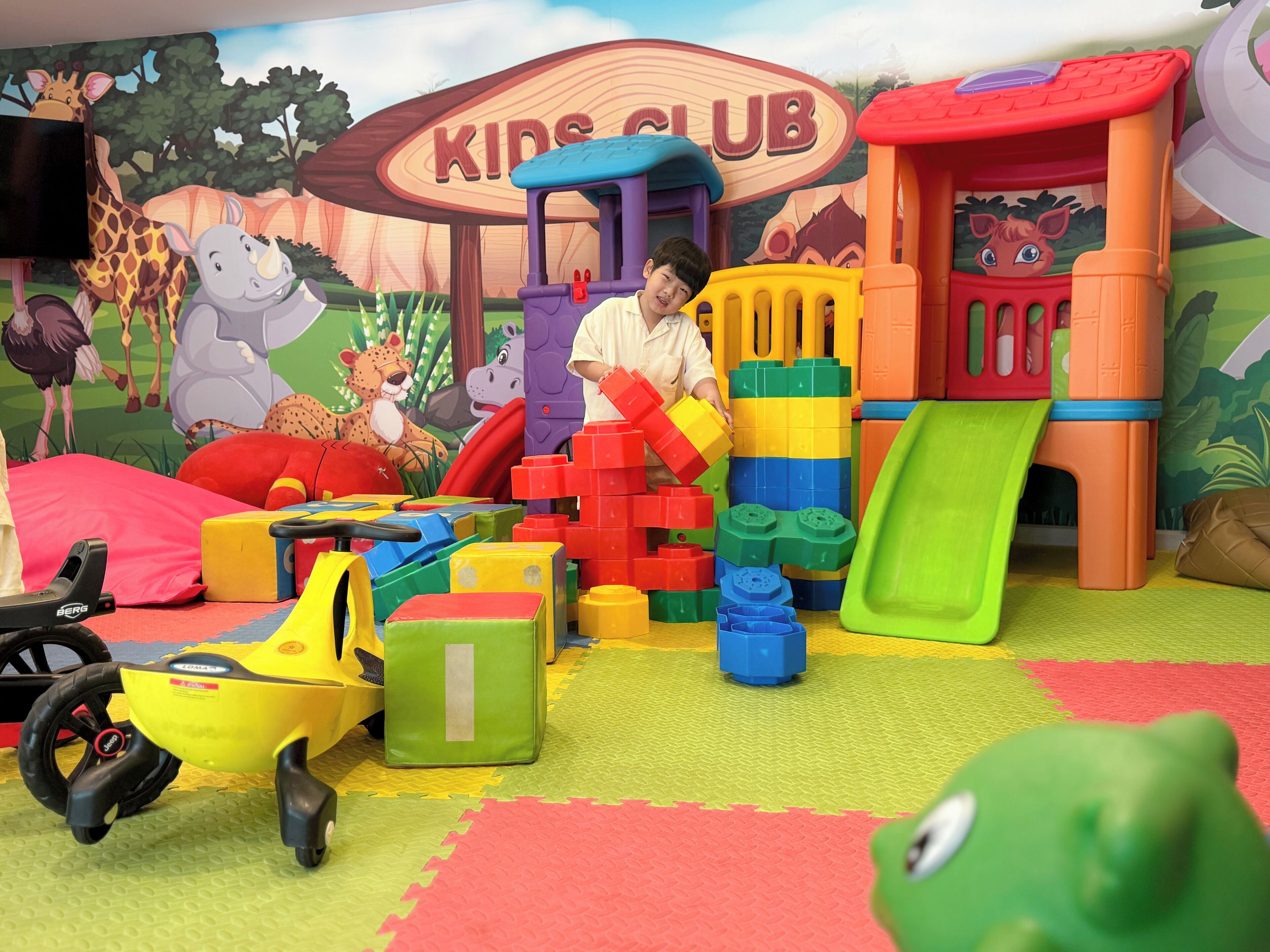 Un área de juegos con bloques de construcción de colores, un tobogán y un coche de juguete.