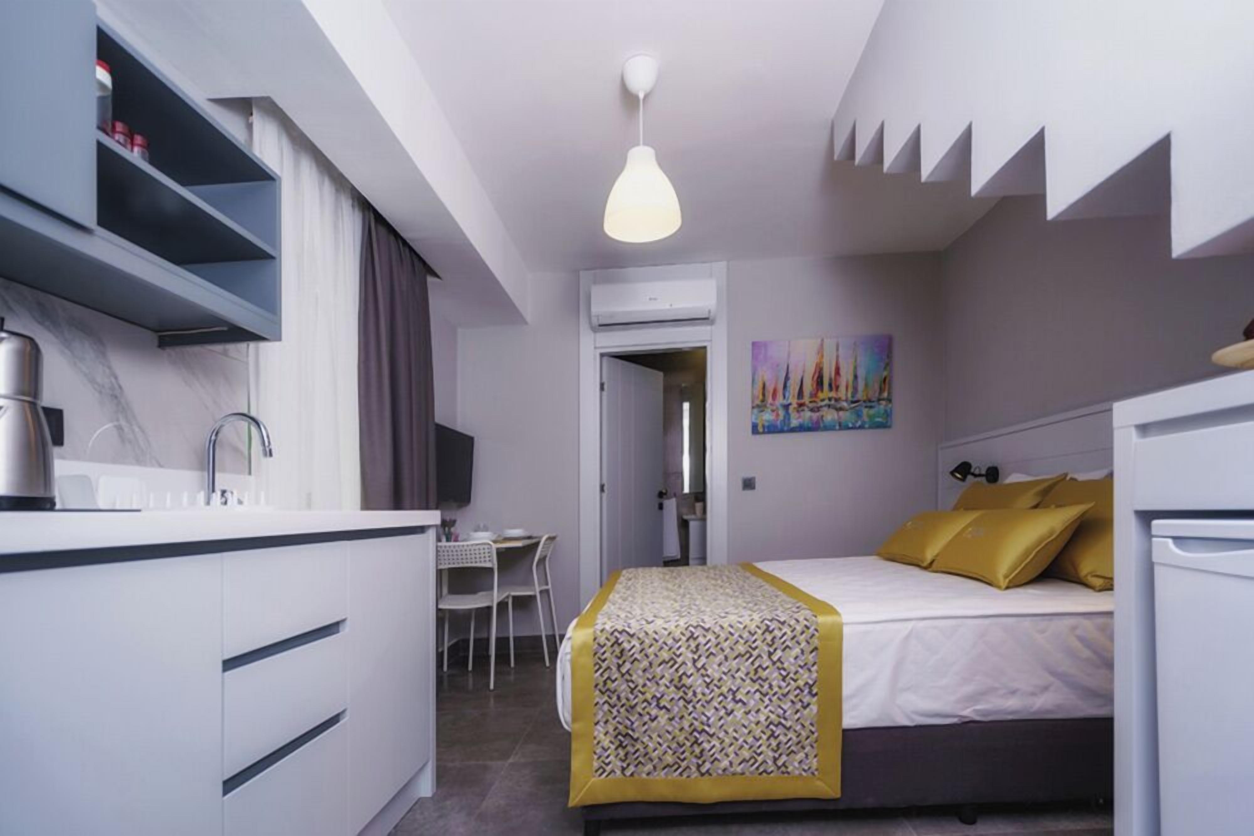 A modern hotel room with a bed, bedside table, and a desk with a chair.