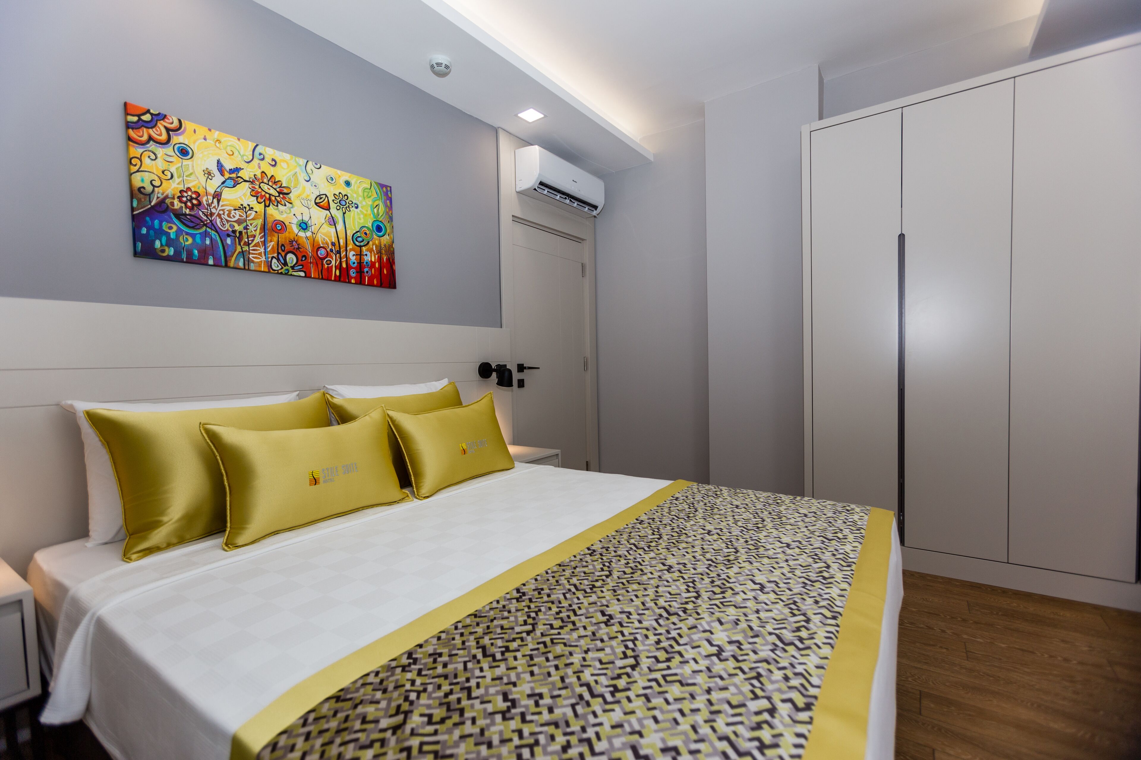 Een hotelkamer met een bed, een schilderij aan de muur, een airconditioning en een kledingkast.
