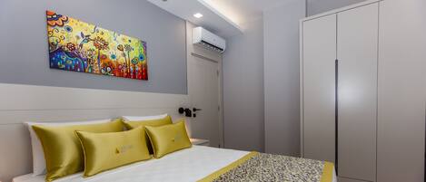 Een hotelkamer met een bed, een schilderij aan de muur, een airconditioning en een kledingkast.