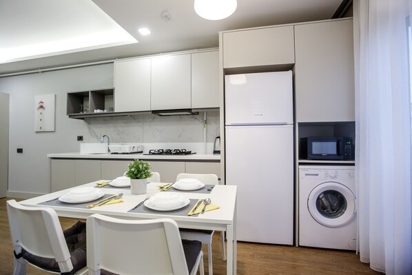 A modern kitchen with white cabinets, a built-in microwave, and a washing machine.