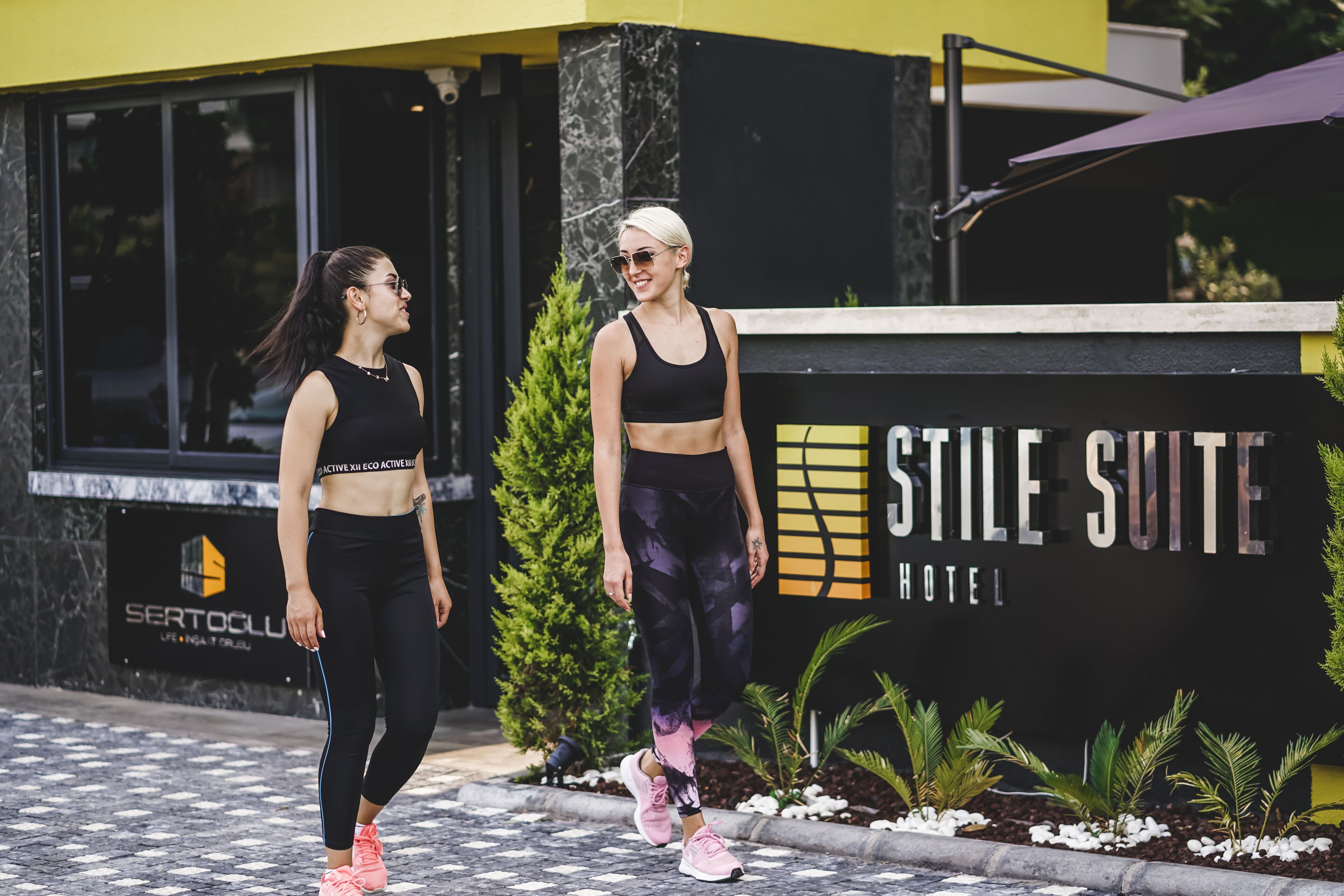 To personer går foran en bygning med et skilt, der står 'STILE SUITE HOTEL'.