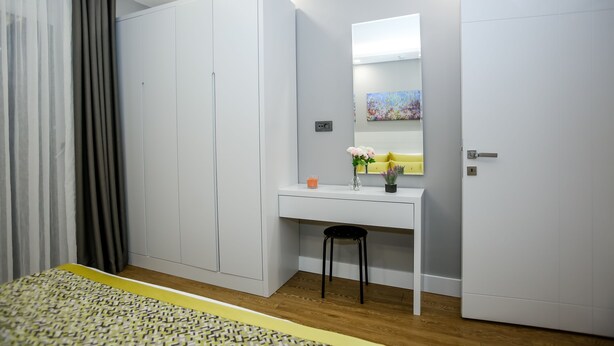 Une chambre à coucher comprenant un lit, un bureau, une chaise, une armoire et un miroir.