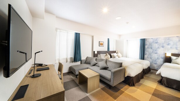 A hotel room with a large flat-screen TV, a sofa, a bed, and a desk. - KOKO HOTEL Sapporo Odori (Sapporo)