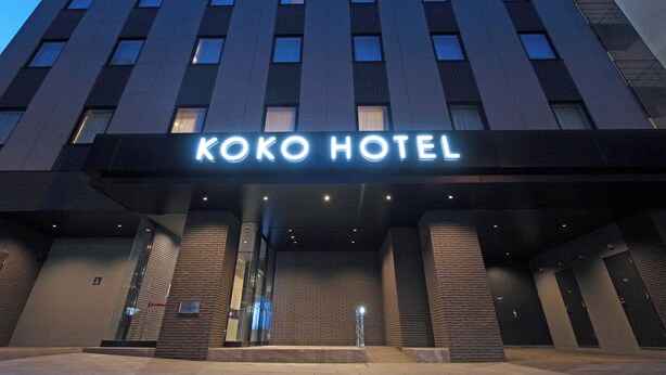 L'esterno dell'Hotel Koko, dal design moderno, con un ingresso ben visibile e una insegna sopra le porte.