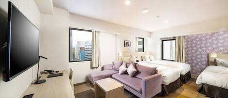 A hotel room with a large flat-screen TV, a sofa, two beds, a desk, and a checkered floor.