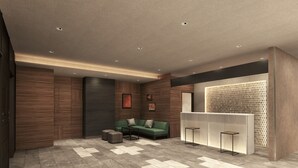 Una hall moderna con un divano verde, due poggiapiedi, una reception e una parete decorata.