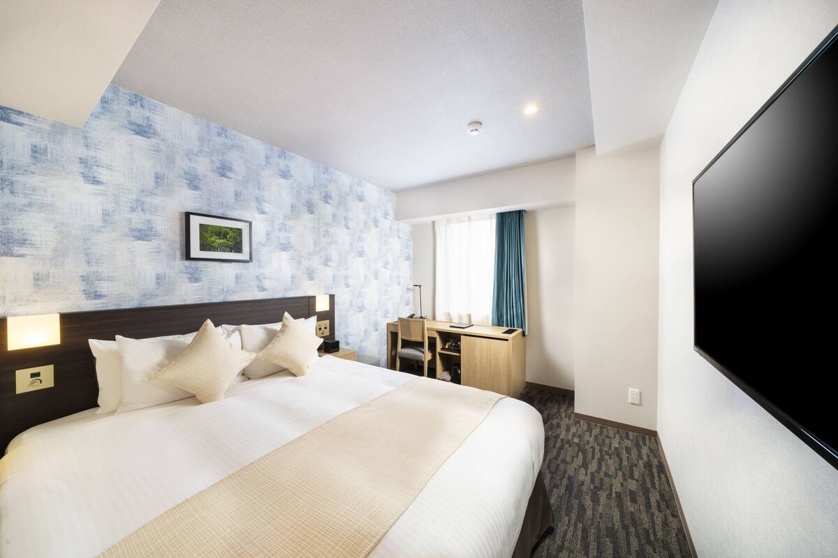 A hotel room with a large bed, a desk, a flat-screen TV, and a picture on the wall.