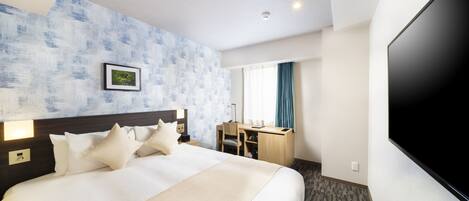 Une chambre d’hôtel avec un grand lit, un bureau, un téléviseur à écran plat et un tableau au mur.