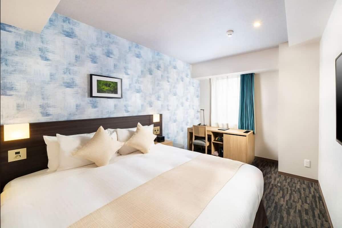 A hotel room with a bed, desk, and TV.