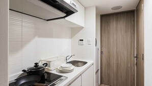 A compact kitchen with white cabinets, a built-in stove, a sink, and a wooden door.