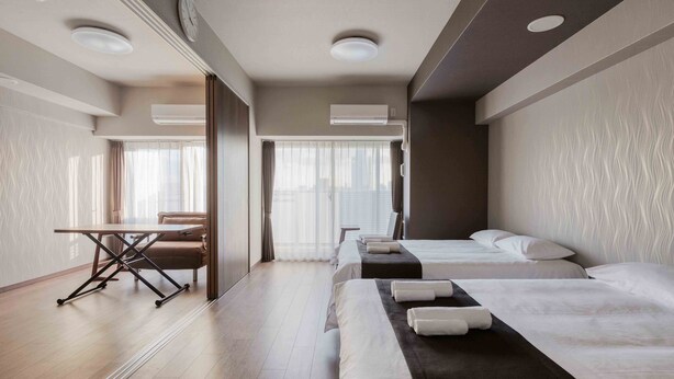 A hotel room with two beds, a desk, and a chair.