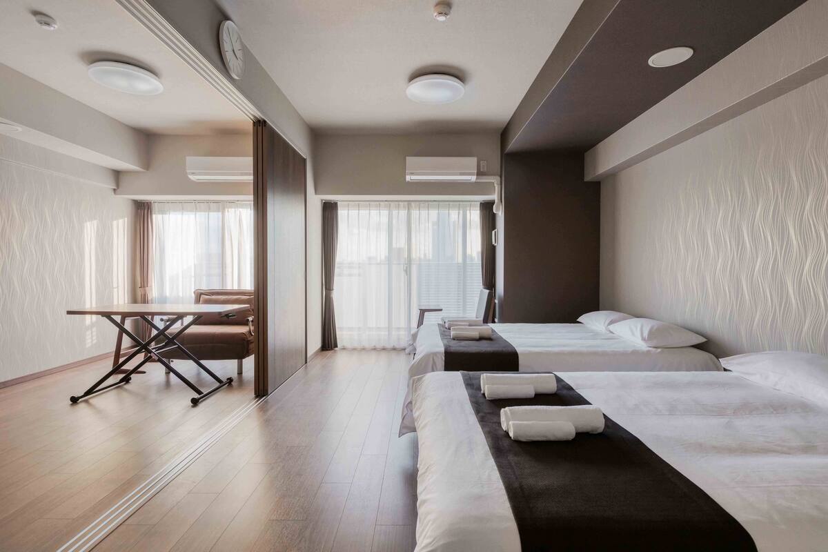 Ein Hotelzimmer mit zwei Betten, einem Schreibtisch und einem Stuhl.