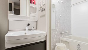 A modern bathroom with a white sink, mirror, and shower.